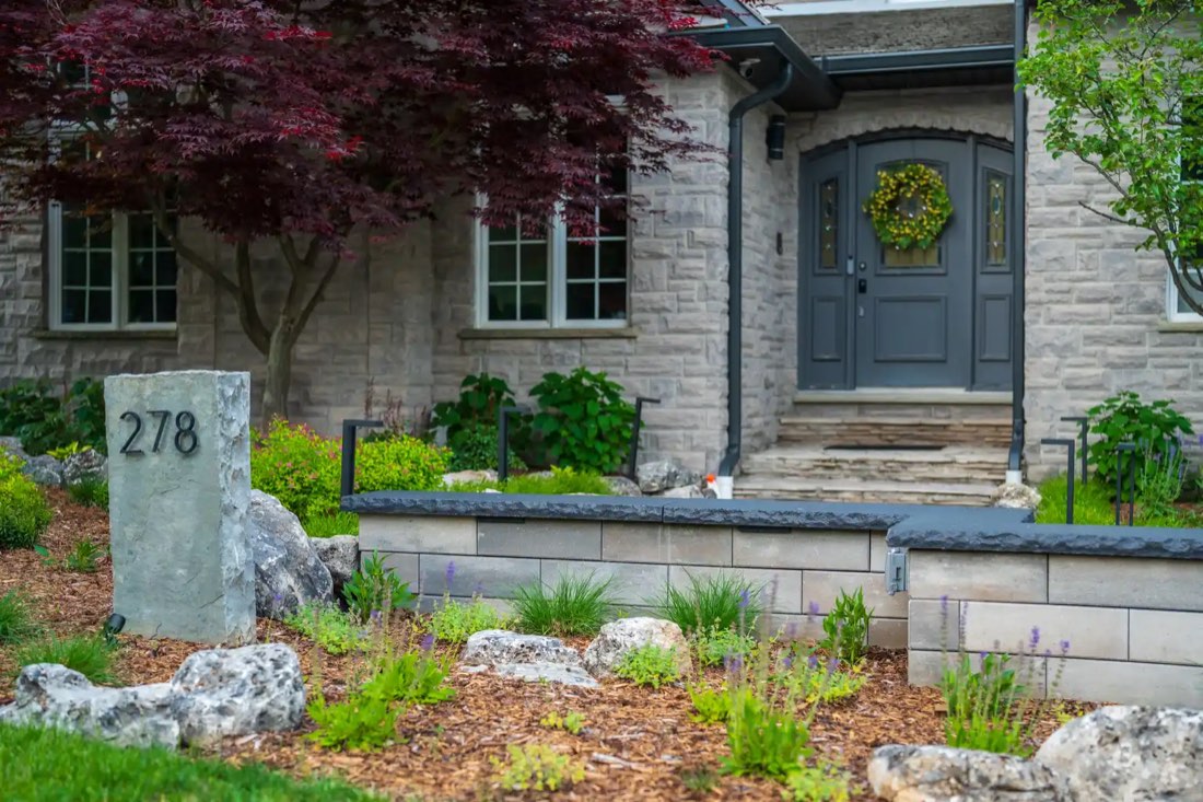 Stone house entrance with boulder garden and address stone at dusk