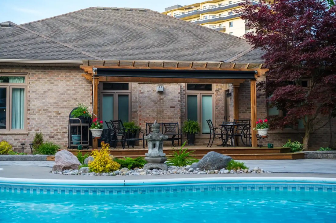 Pergola seating area beside the pool with planters