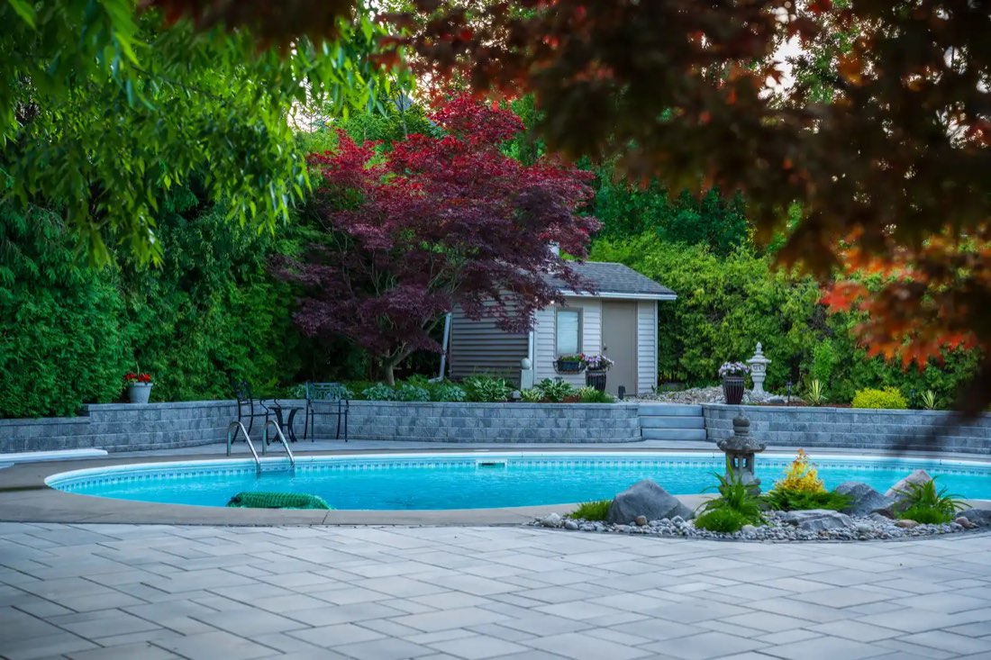 Pool with fountains, stone wall and Japanese maple at dusk