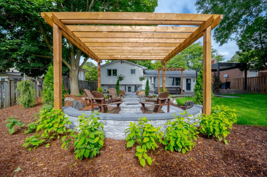A cedar pergola over a stone fire-pit seating area