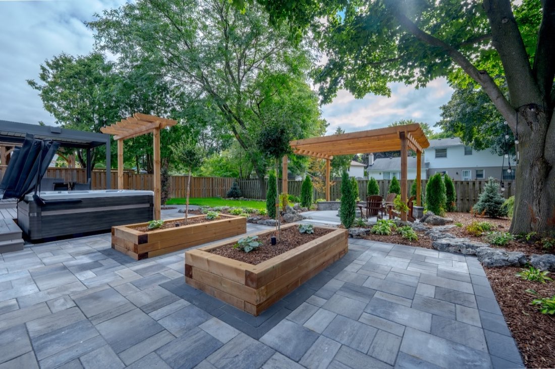 Wide paver patio with hot tub and cedar planter beds