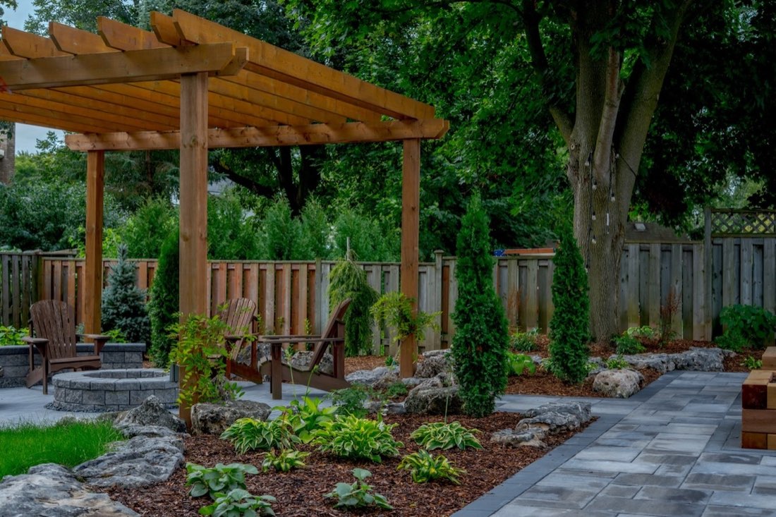 Pergola seating area with layered plantings and armour stone