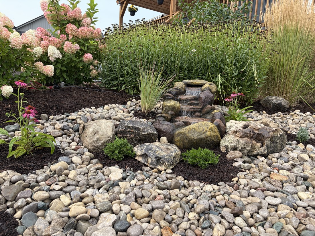 Bubbling rock fountain surrounded by grasses and coneflowers