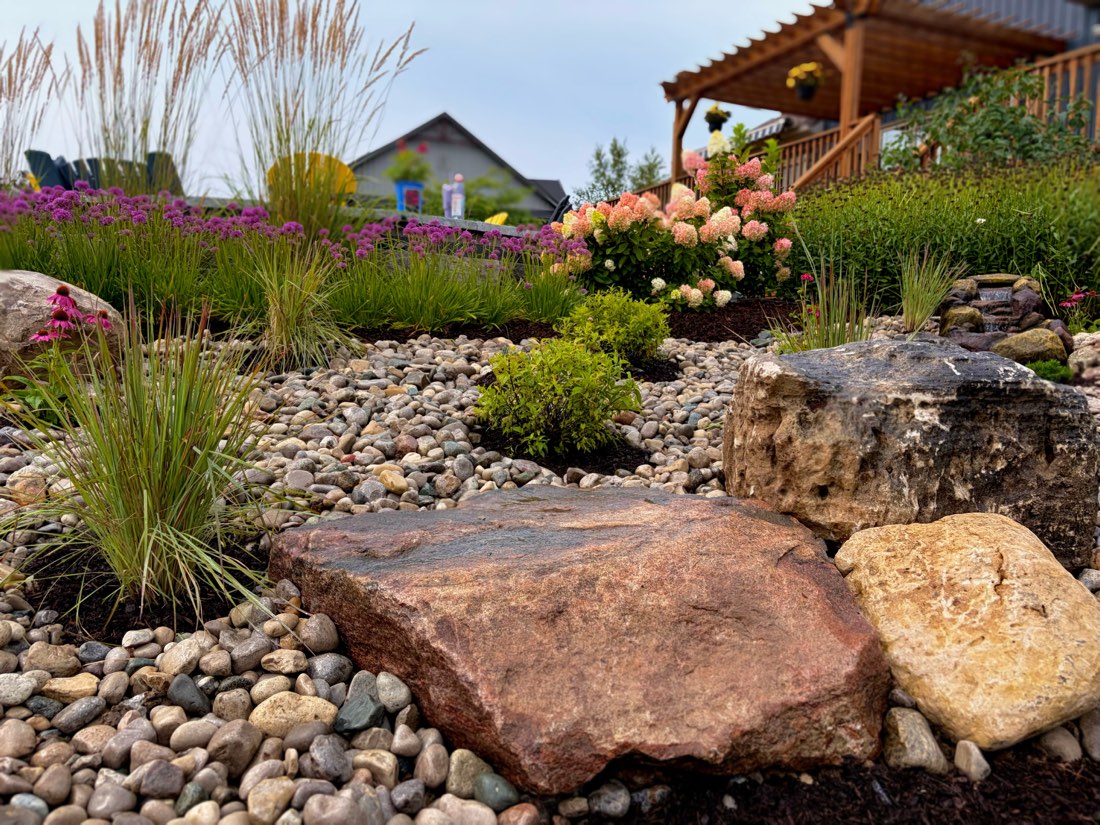 Bubbling rock with hydrangeas and purple salvia behind