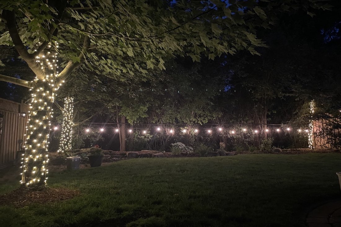 A backyard glowing with warm string lights at night